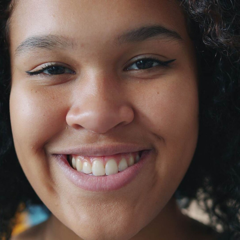 Young woman with a bright, natural smile, representing family dental care at Sunshine Smiles Dental Clinic